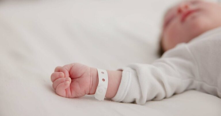 Baby,,New,Born,And,Hand,With,Bracelet,On,Bed,For